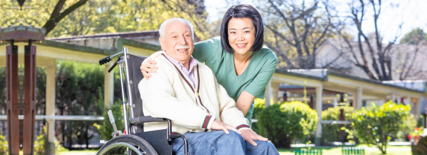 caregiver and senior man on wheelchair are smiling